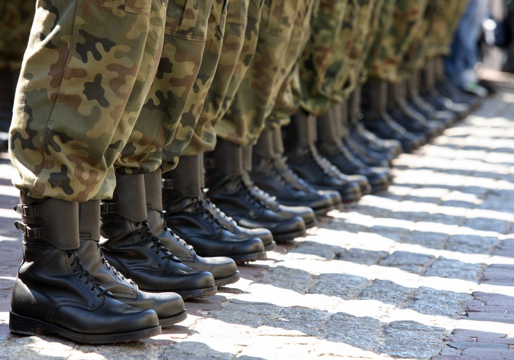 U.S. soldiers stand in a line wearing personal equipment protection. 